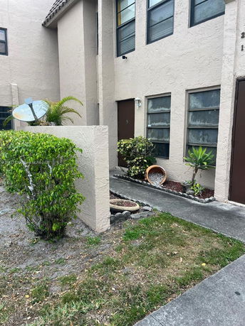 Front view of a multi-story building with a satellite dish and potted plants.