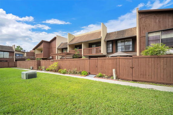 Front view of multi-story homes with balconies and fenced front yards.