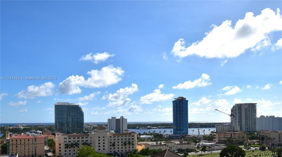 Panoramic view of cityscape with high-rise buildings and a body of water in the background.