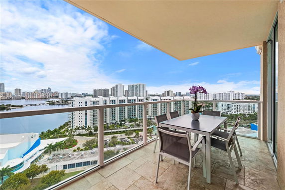 Balcony view overlooking cityscape and waterfront with a dining table set.