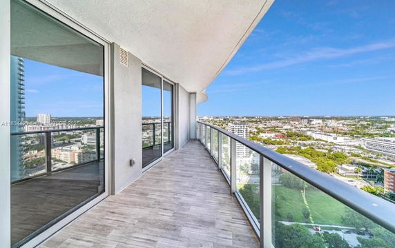 Balcony with glass railing offering panoramic city views.