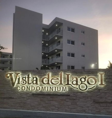 Front view of a condominium building with balconies and illuminated signage.