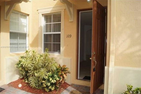 Entrance of a house with beige walls and a brown door.