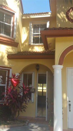 Front view of a yellow two-story house with arched entrance and white columns.