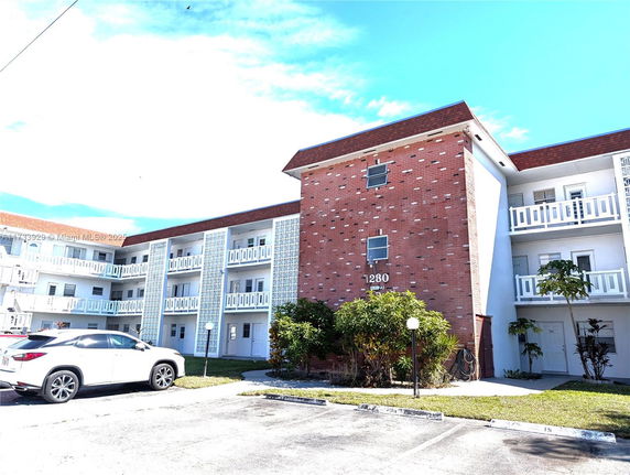 Front view of a three-story building with balconies and brick facade.