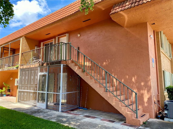 Front view of a two-story building with stairs and a balcony.