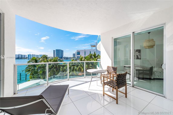 Balcony view with glass railing overlooking water and surrounding buildings.