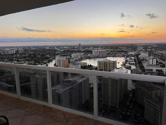 Panoramic view of cityscape with buildings and water from a high vantage point at sunset.