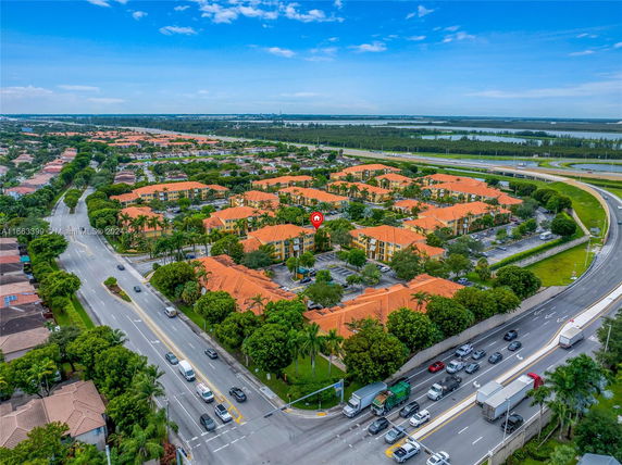 Aerial view of a residential area with multiple buildings with orange roofs, roads, and greenery.