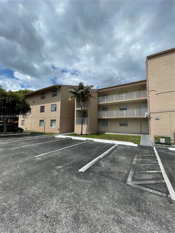 Front view of a multi-story building with adjacent parking spaces.