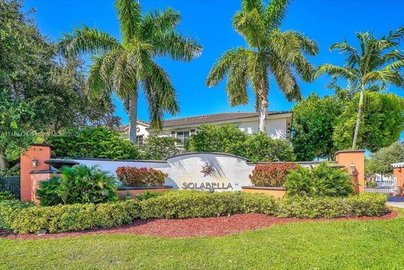 Front view of a residential building with palm trees and a decorative entrance.