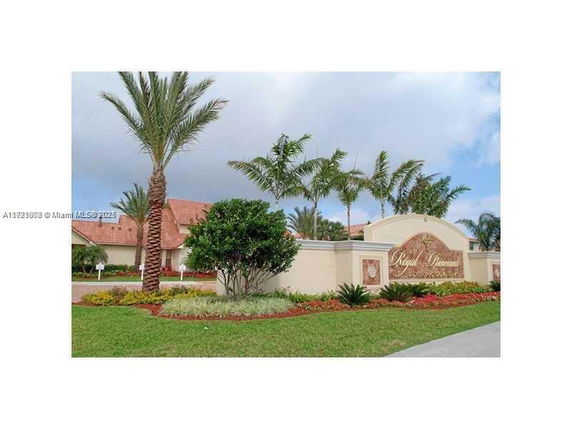 Front view of a building entrance with a decorative sign and landscaped surroundings.