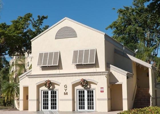 Front view of a gym building with two large windows and an entrance with double doors.
