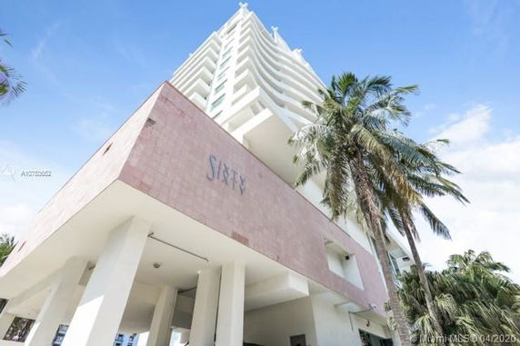 Front view of a multi-story building with balconies and palm trees.