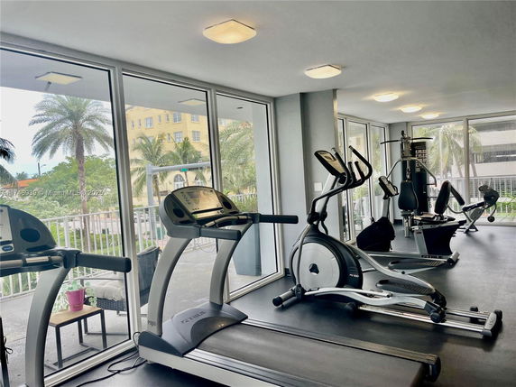 Indoor gym area with exercise machines and large windows.