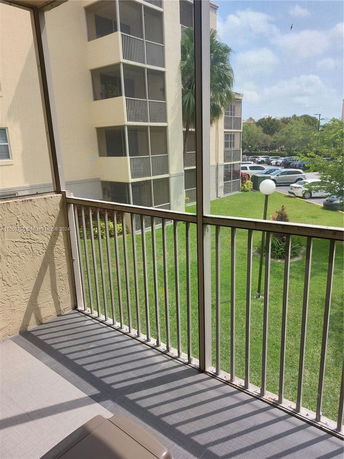 View from a balcony looking at neighboring apartment buildings and a parking area.