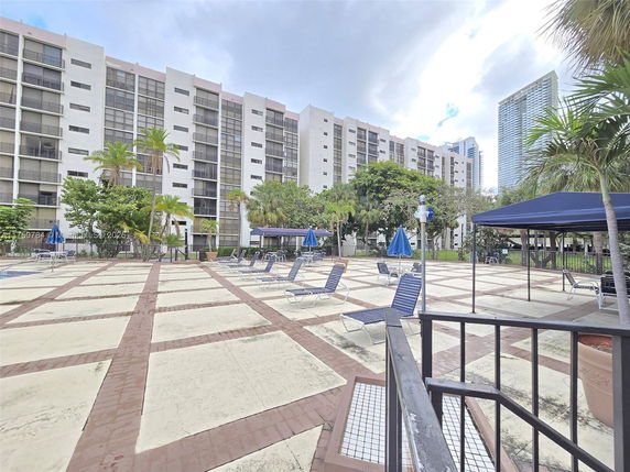 Outdoor view of a multi-story residential building with a swimming pool area in the foreground.