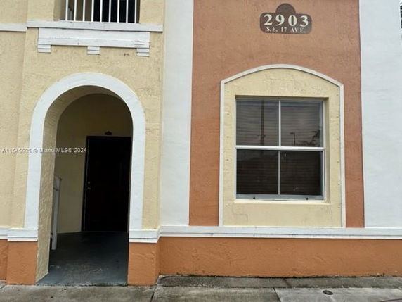 Front view of a building with an arched entrance and a window next to it.