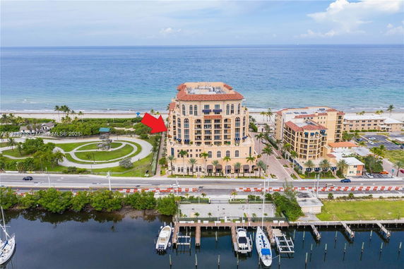 Front view of a multi-story beachfront building with balconies and decorative architecture.