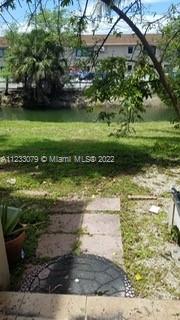 View from a yard area with grass and trees, overlooking a waterway and buildings in the background.