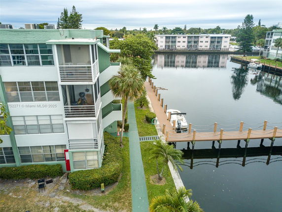 View of an apartment building near a waterfront with a dock and small boats.