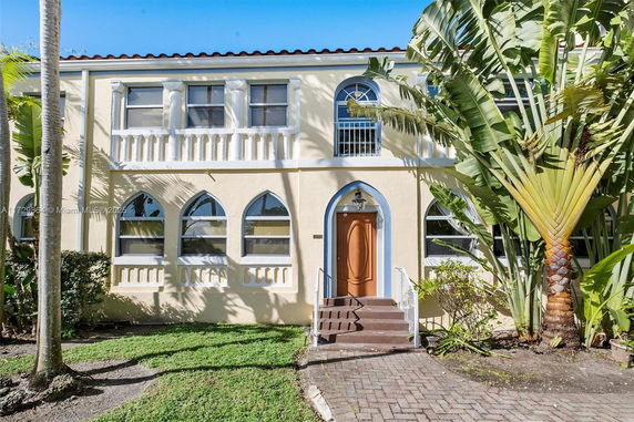 Front view of a two-story house with arched windows and a small staircase leading to the main entrance.
