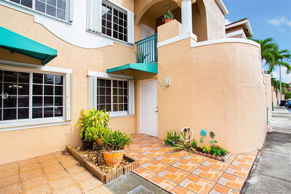 Front view of a two-story house with arched design and teal awnings.
