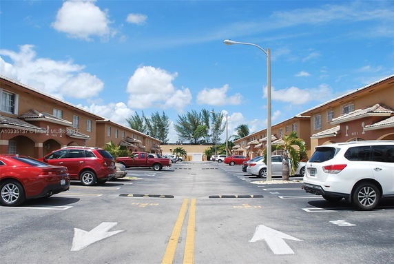 Outdoor parking area with parked cars in front of residential buildings.