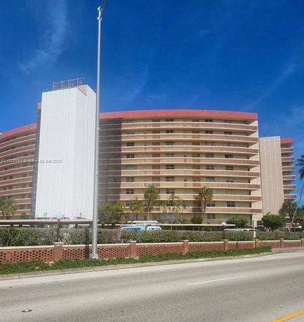 Front view of a multi-story curved apartment building with a red roof.