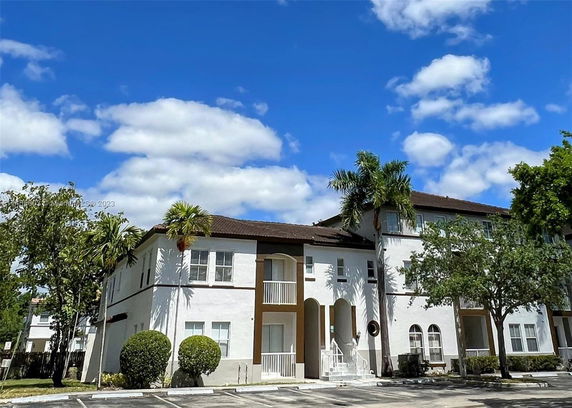Front view of a two-story building with arched entrances and palm trees.
