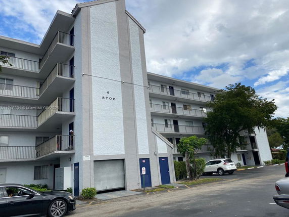Front view of a multi-story residential building with balconies and parking area.