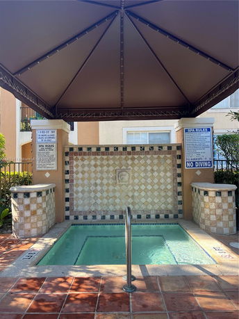 Small outdoor spa pool with canopy and decorative tile wall.