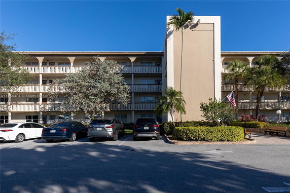 Front view of a multi-story residential building with balconies and parking spaces.