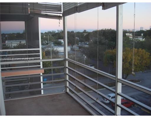 View from a balcony showing surrounding residential area and distant trees.
