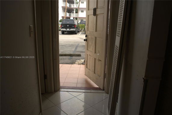 View from a doorway showing an outdoor parking area with a parked vehicle.