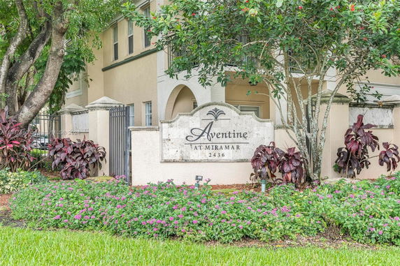 Front view of a building with a sign reading 'Aventine at Miramar 2436', surrounded by plants.