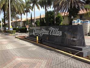 Front view of a villa complex entrance sign with palm trees.