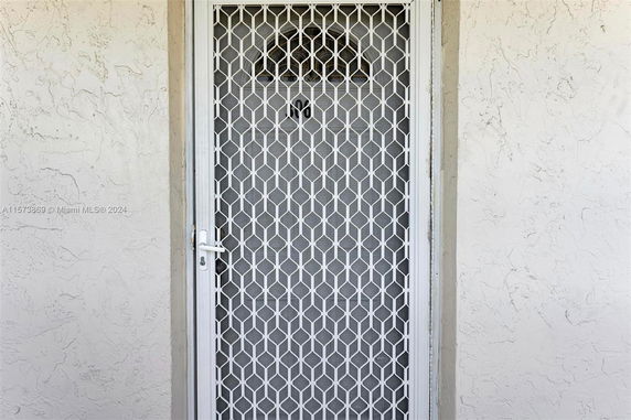 Front view of a door with a white metal security screen.