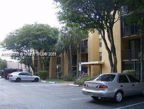 Front view of a multi-story residential building with parked cars in front.
