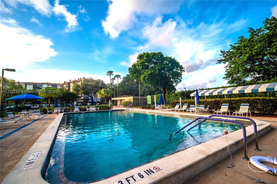 Outdoor swimming pool with lounge chairs and umbrellas.