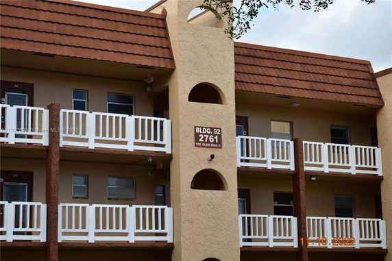 Front view of a multi-story building with balconies and brown tiled roof.
