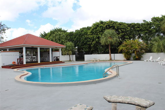 Outdoor swimming pool with a nearby pavilion and lounge chairs.