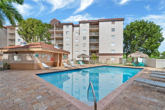 Outdoor swimming pool in front of a multi-story residential building.