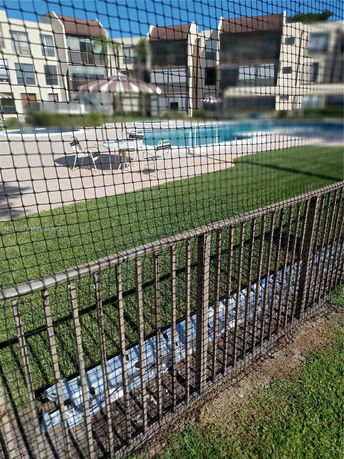View of an outdoor swimming pool with surrounding buildings and patio furniture.
