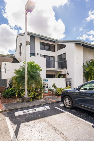 Front view of a modern two-story building with a parking area in front.