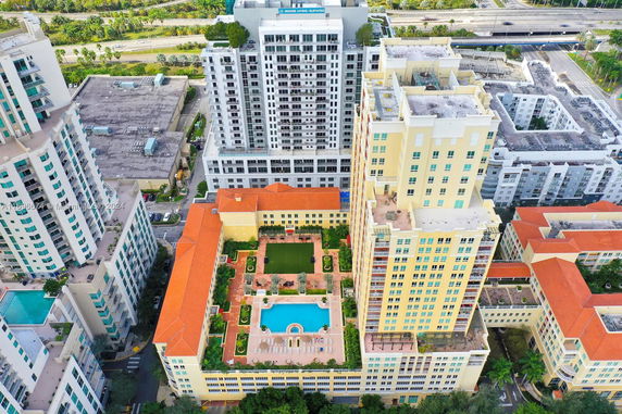 Aerial view of a complex with multiple buildings and a rooftop featuring a swimming pool.