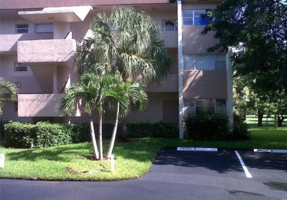 Front view of a multi-story building with balconies and palm trees.