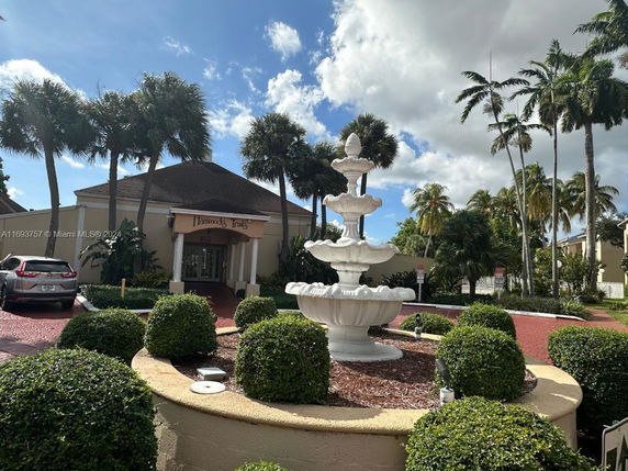 Front view of a building with a tiered fountain and palm trees.