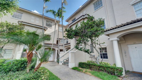 Front view of a multi-story residential building with stucco exterior and arched entryways.