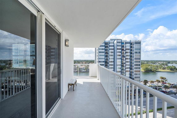 Balcony view from a high-rise building overlooking a nearby structure and a body of water.